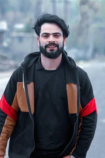 Original portrait of Leo, an editorial alias, with a high dark quiff, full beard and a multicolored hooded jacket.