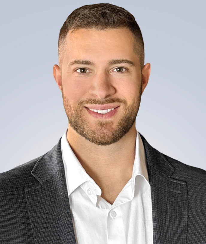 Original front-facing portrait with short textured hair, a neat beard, gray checked blazer and open-collar white shirt.